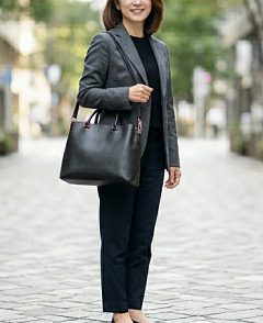 グレーの上着を着て黒い2wayトートバッグを肩に掛けた女性