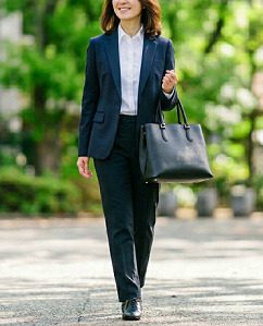 スーツを着て、黒のトートバッグを持って通勤する女性