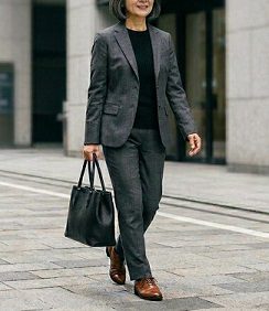ビジネススーツを着て、黒のトートバッグを持って通勤する女性