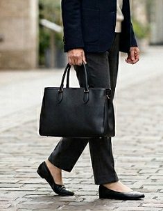 街中で、黒い横型のトートバッグを持ち歩く女性の様子