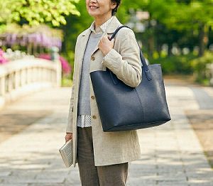 紺色のトートバッグを肩に掛けている女性