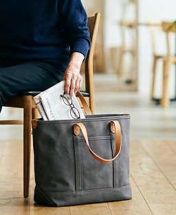 女性が椅子横で自立しやすいトートバッグに荷物を出し入れしている様子