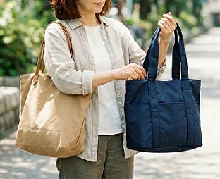女性が、肩にベージュのトートバッグをかけ、手に持ったネイビーのトートバッグの中身を確認している様子