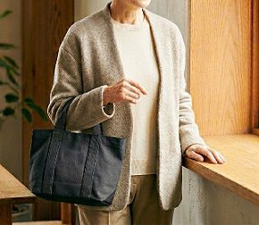 室内でシンプルな黒のトートバッグを持つ女性