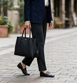 街中で黒い品のあるトートバッグを持ち歩く女性の様子