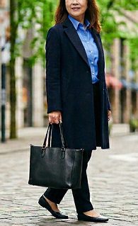 黒いトートバッグを持って、街中を歩く女性の様子