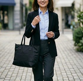 黒いトートバッグを持って、街中を歩く女性のイメージ