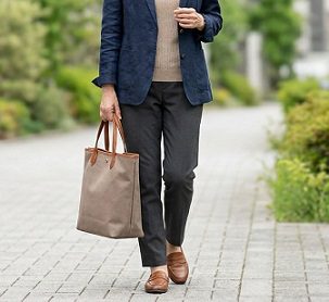 縦型のトートバッグを持って歩く女性